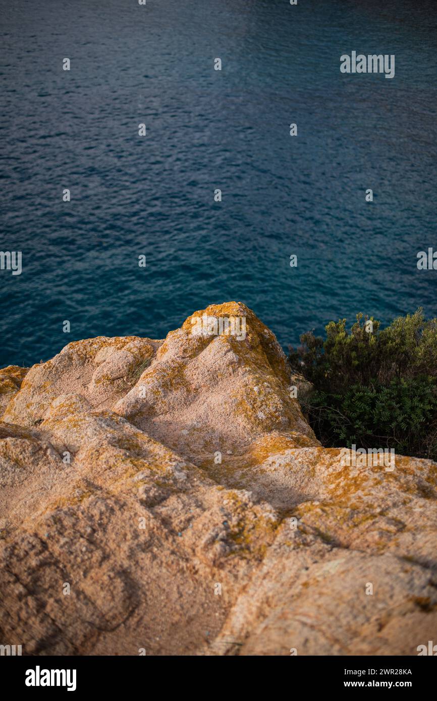 Lichen jaune poussant sur une falaise rocheuse surplombant la mer bleue des Baléares Banque D'Images