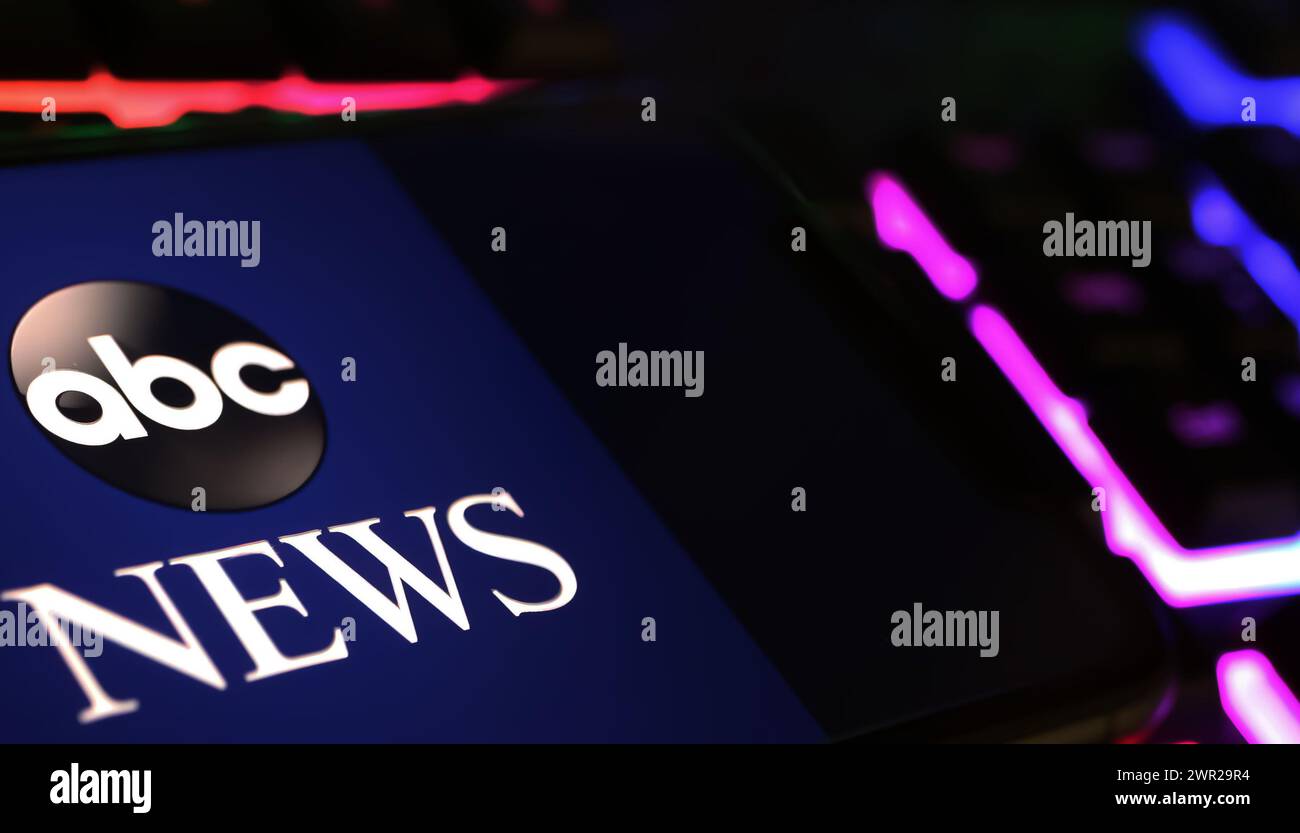 Viersen, Allemagne - 1er mars. 2024 : gros plan de smartphone avec lettrage logo de ABC amercian Broadcasting News sur clavier d'ordinateur Banque D'Images