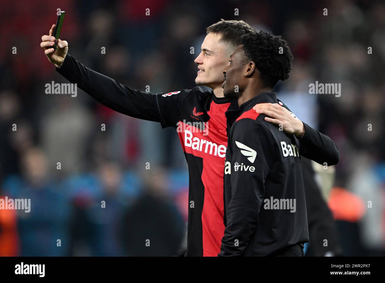 Leverkusen, Allemagne. 10 mars 2024. Football : Bundesliga, Bayer Leverkusen - VfL Wolfsburg, journée 25, dans la BayArena. Florian Wirtz de Leverkusen (g) et Nathan Tella prennent une photo avec un téléphone portable. Crédit : Federico Gambarini/dpa - NOTE IMPORTANTE: conformément aux règlements de la DFL German Football League et de la DFB German Football Association, il est interdit d'utiliser ou de faire utiliser des photographies prises dans le stade et/ou du match sous forme d'images séquentielles et/ou de séries de photos de type vidéo./dpa/Alamy Live News Banque D'Images