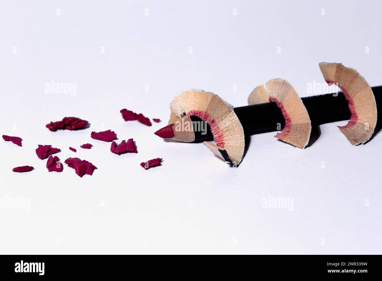 Crayon à lèvres rose affûté avec copeaux en spirale sur une surface blanche Banque D'Images