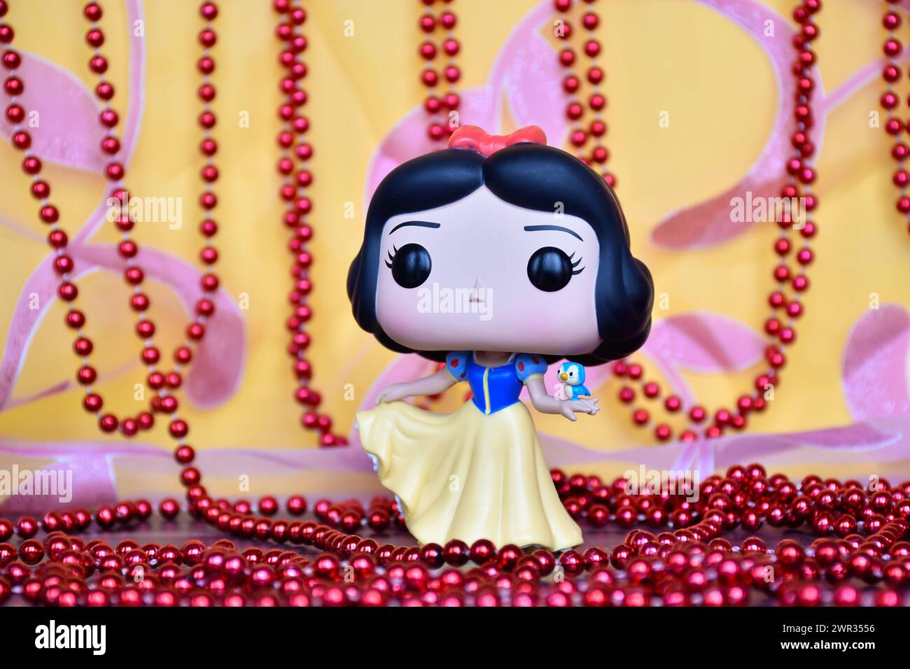 Funko Pop figurine de Disney princesse Blanche-neige avec oiseau. Rideau rose doré, décor collier rouge, fabuleux palais. Banque D'Images