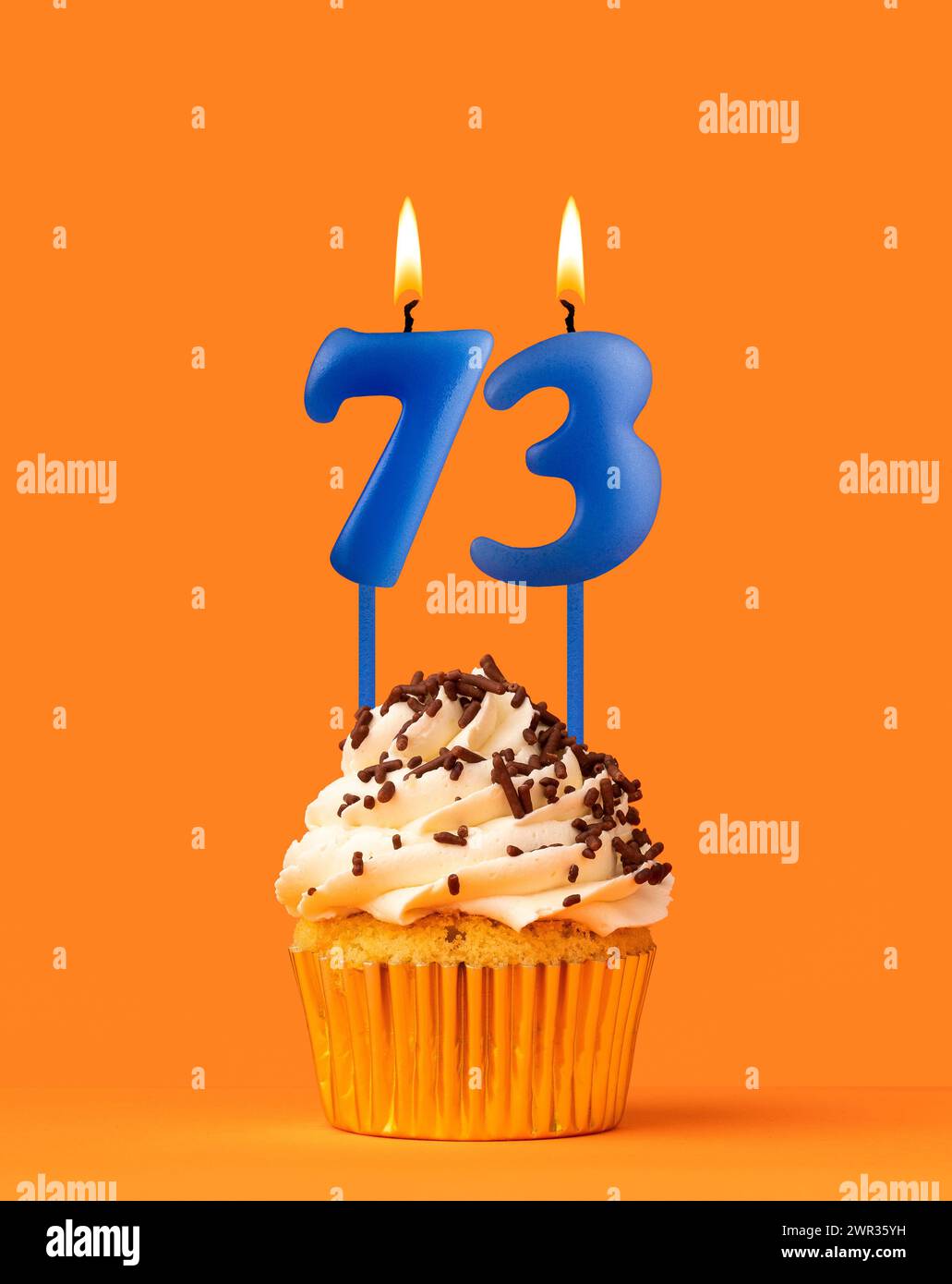 Bougie bleue numéro 73 - cupcake d'anniversaire sur fond orange Banque D'Images