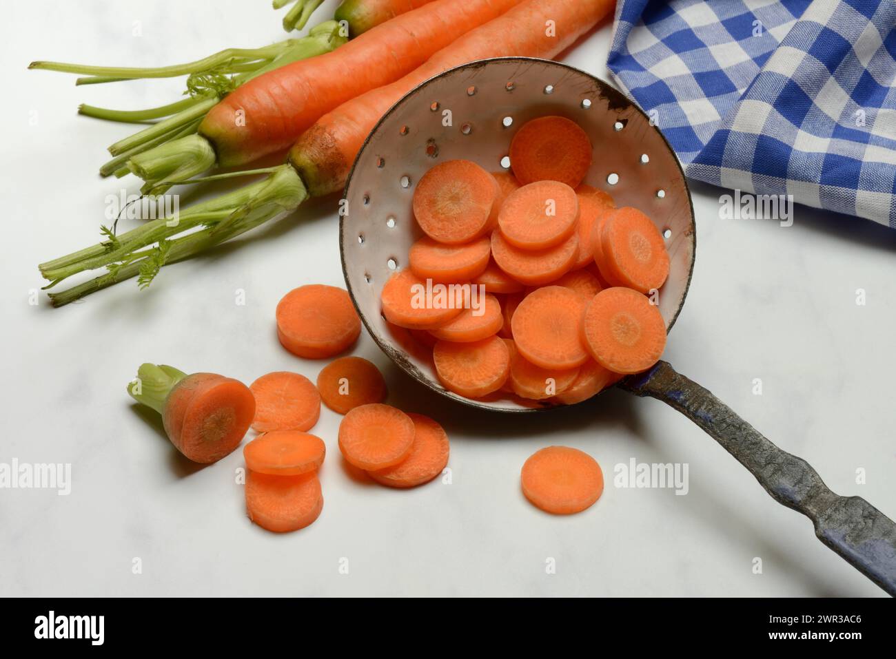 Tranches de carottes en passoire et cuillère en bois, Daucus carota Banque D'Images