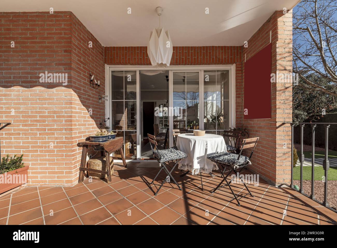 Porche d'une maison résidentielle avec table à manger avec chaises pliantes et portes vitrées menant à la maison Banque D'Images