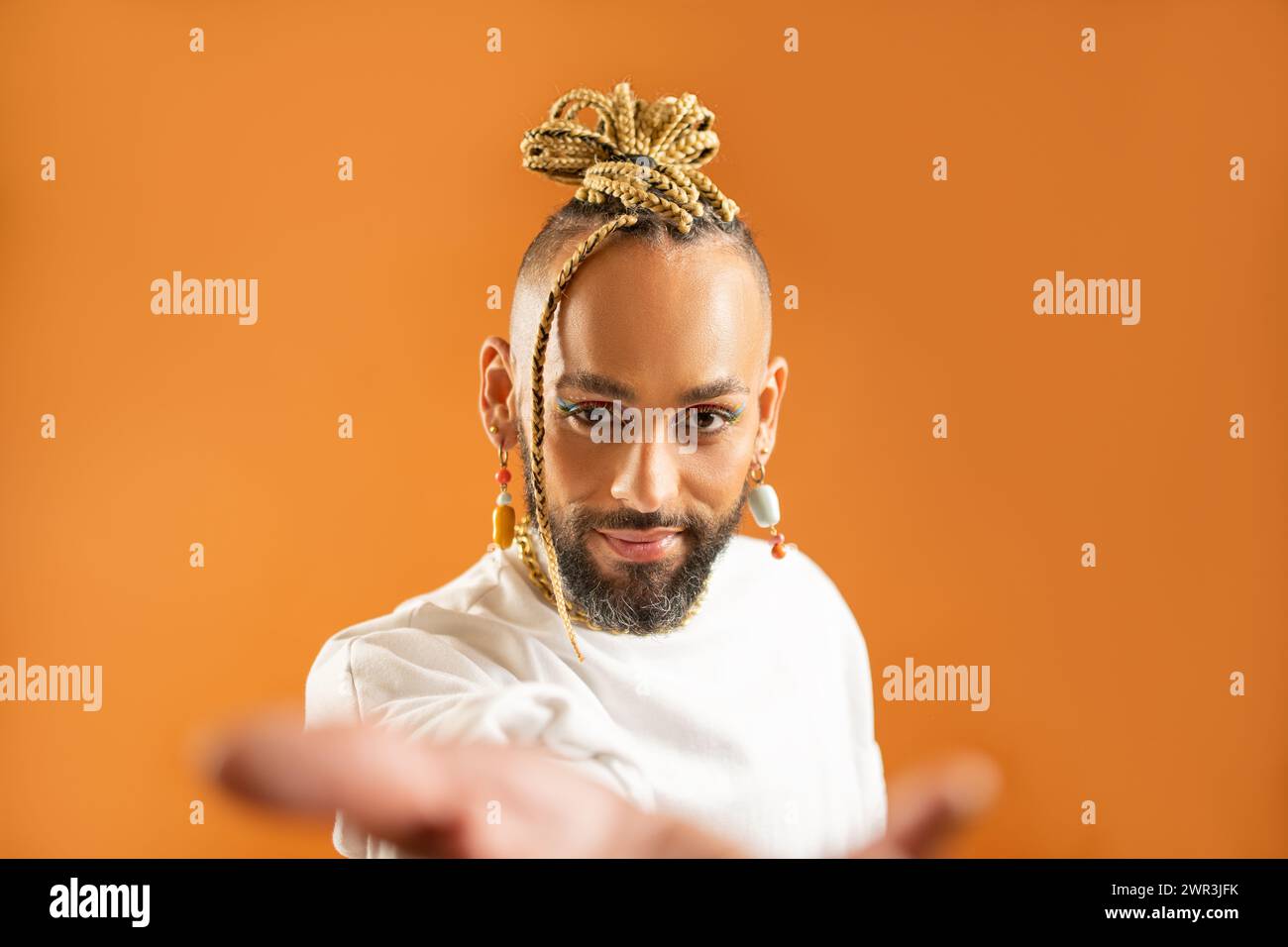 Gay afro-américain au maquillage brillant atteignant la main vide de la paume ouverte vers la caméra. Concept de publicité maquette. Homme homosexuel étirant la main vide vers la caméra. LGBT Helping Banque D'Images