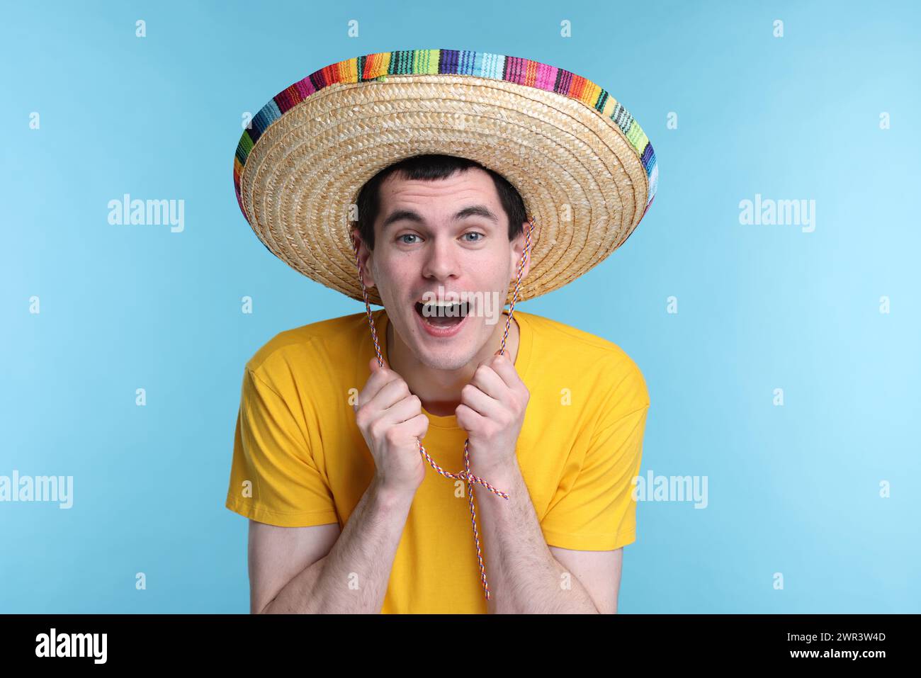 Jeune homme dans le chapeau sombrero mexicain sur fond bleu clair Banque D'Images