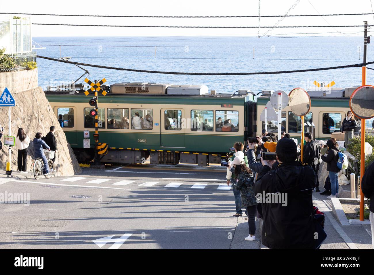 Les touristes prennent des photos autour du passage à niveau de la gare Kamakura Kokomae d'Enoden dans la ville de Fujisawa, préfecture de Kanagawa, le 28 février 2024. Ce passage à niveau est présenté dans la célèbre série d'animation japonaise 'Slam Dunk'. C'est une destination touristique populaire pour les touristes nationaux et étrangers à visiter et à prendre des photos. Cependant, en raison du grand nombre de touristes visitant le train d'Enoden est devenu extrêmement fréquenté, et les résidents vivant le long de la ligne ont été touchés par le problème du surtourisme. Crédit : Yosuke Tanaka/AFLO/Alamy Live News Banque D'Images