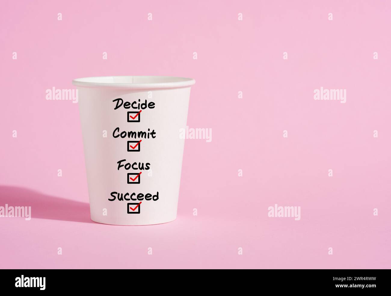 Décidez, engagez, concentrez-vous et réussissez sur une tasse de café en papier sur fond rose. Processus motivant ou inspirant pour réussir dans les affaires de la vie. Par Banque D'Images