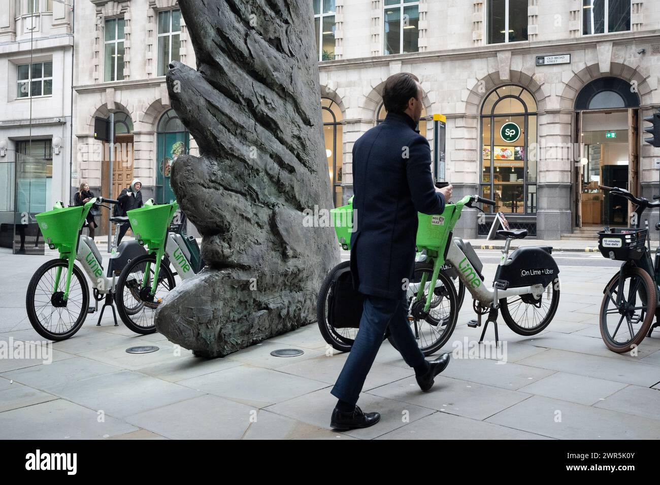 Les employés de la ville passent devant la sculpture intitulée « City Wing » et les vélos de location Lime sur Threadneedle Street dans la ville de Londres, le quartier financier de la capitale (alias Square Mile), le 7 mars 2024, à Londres, en Angleterre. 'City Wing' est de l'artiste Christopher le Brun. La sculpture en bronze de dix mètres de haut a été réalisée par Christopher le Brun, président de la Royal Academy of Arts, commandé par Hammerson en 2009. Elle est appelée « The City Wing » et a été moulée par Morris Singer Art Founders, réputée être la plus ancienne fonderie d’art au monde. Banque D'Images
