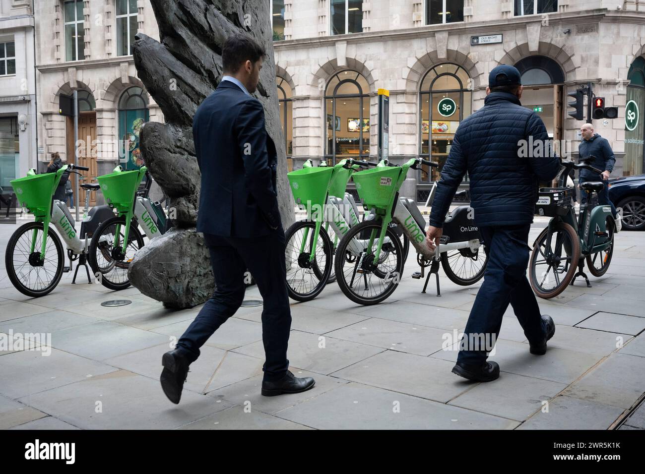 Les employés de la ville passent devant la sculpture intitulée « City Wing » et les vélos de location Lime sur Threadneedle Street dans la ville de Londres, le quartier financier de la capitale (alias Square Mile), le 7 mars 2024, à Londres, en Angleterre. 'City Wing' est de l'artiste Christopher le Brun. La sculpture en bronze de dix mètres de haut a été réalisée par Christopher le Brun, président de la Royal Academy of Arts, commandé par Hammerson en 2009. Elle est appelée « The City Wing » et a été moulée par Morris Singer Art Founders, réputée être la plus ancienne fonderie d’art au monde. Banque D'Images