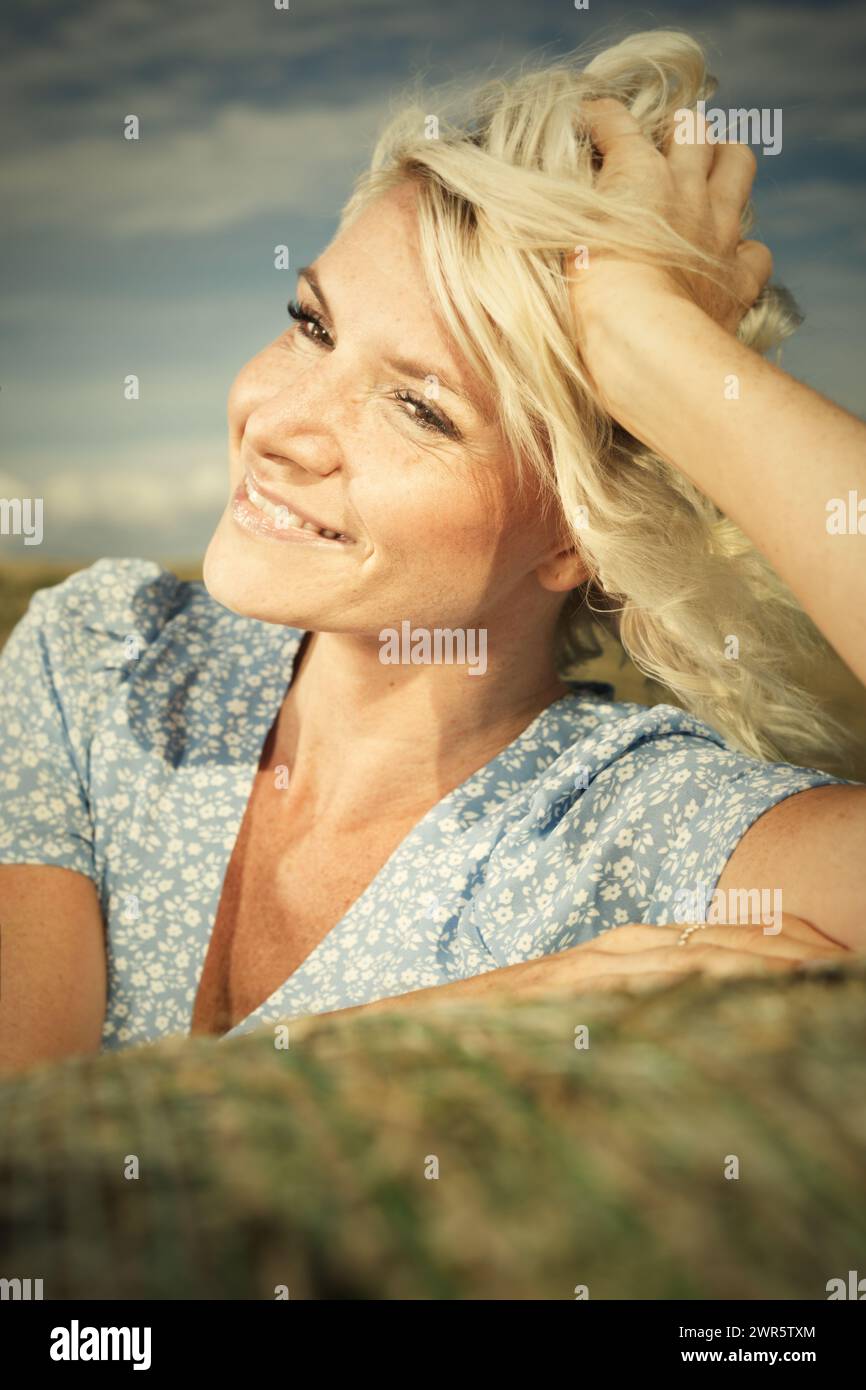 Jolie dame en vêtements d'été posant sur un champ de maïs récolté Banque D'Images