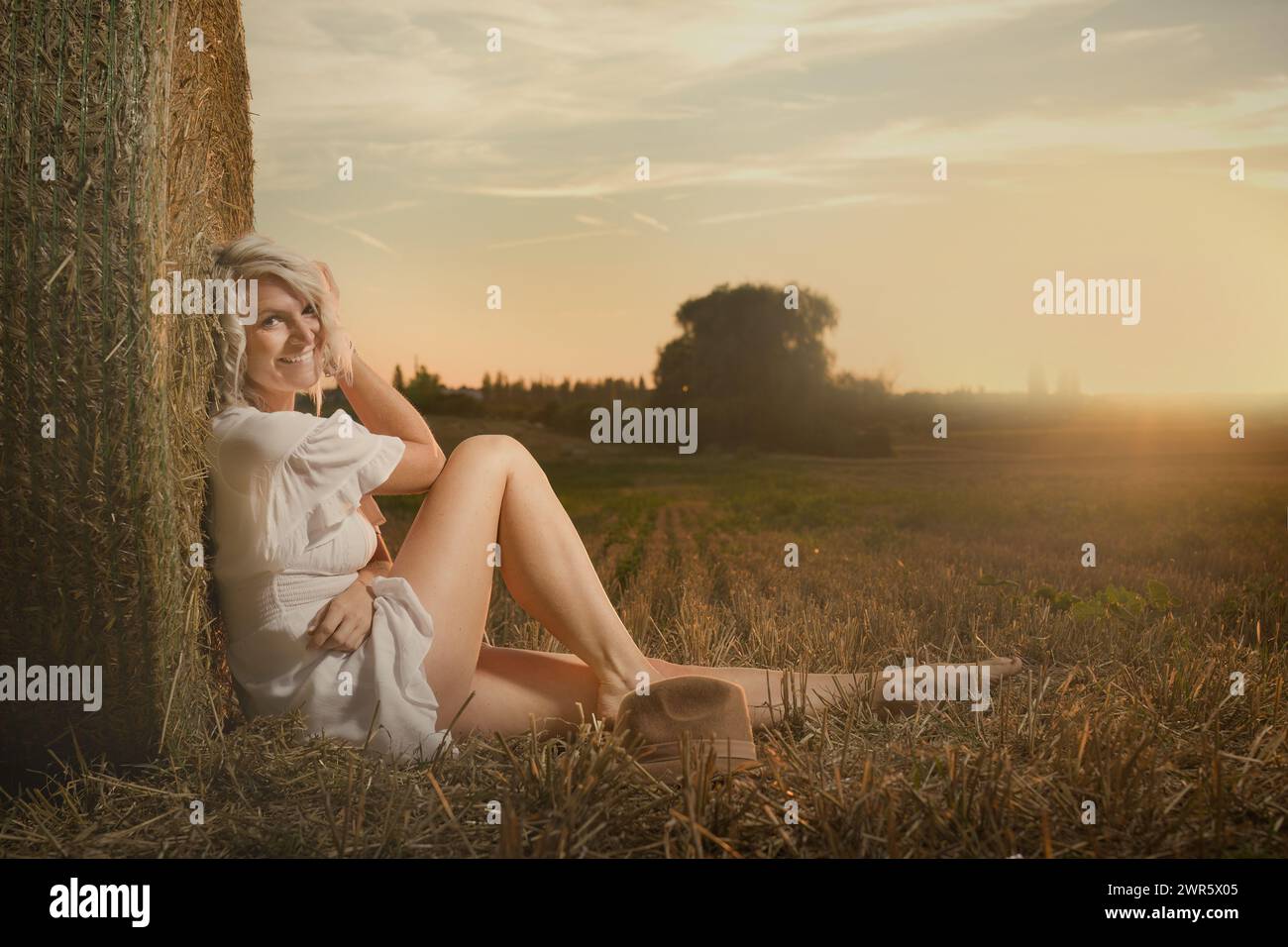 Jolie dame en vêtements d'été posant sur un champ de maïs récolté Banque D'Images