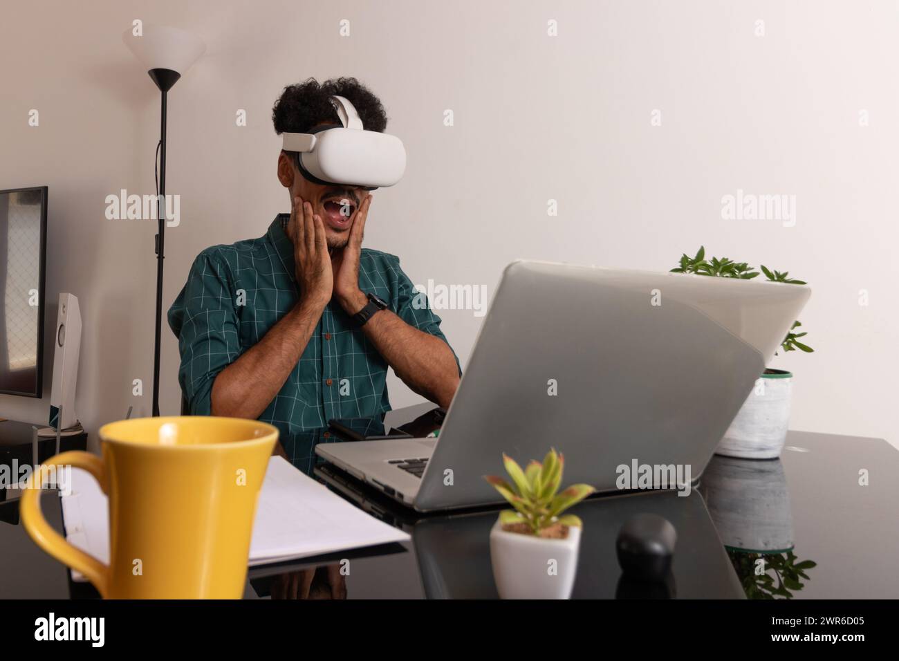 Homme noir portant des lunettes VR à Remote Job. Jeune nomade sur une réunion de télétravail au bureau avec ordinateur portable Banque D'Images