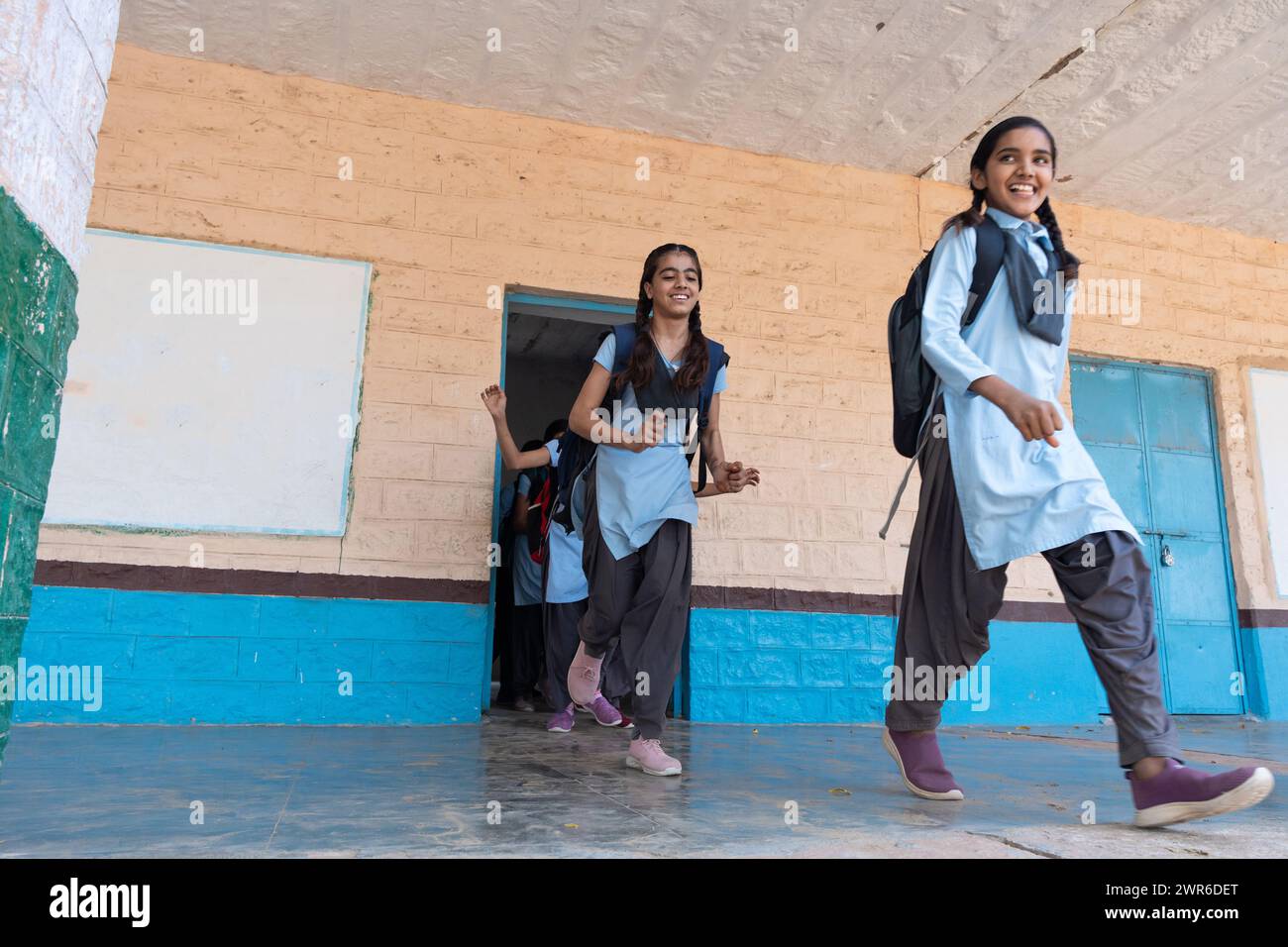 Groupe d'enfants ruraux indiens en uniforme scolaire courant dans le couloir scolaire. Concept d'éducation Banque D'Images