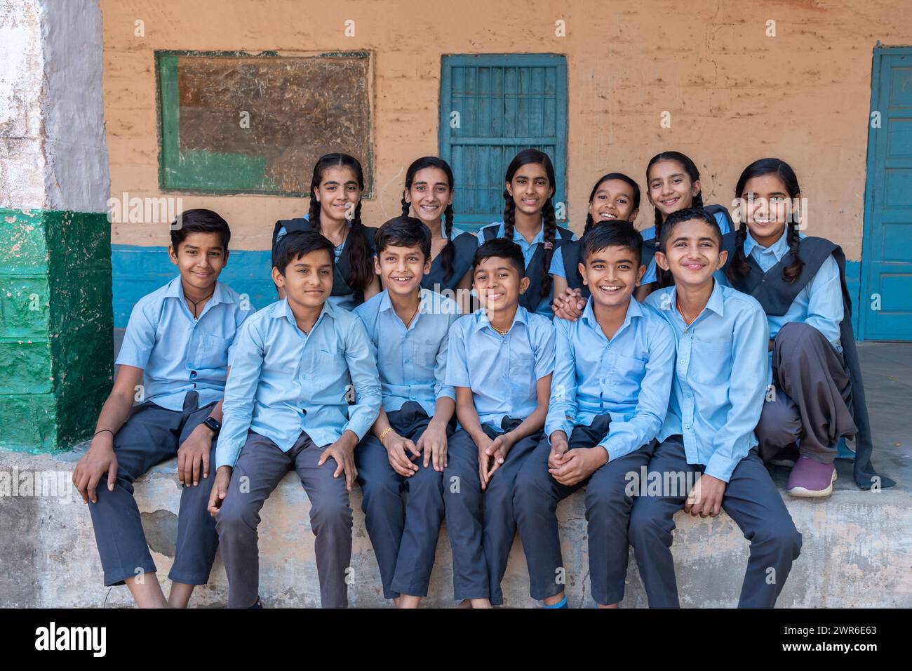 Groupe d'élèves indiens ruraux assis ensemble dans l'uniforme bleu de l'école regardant la caméra Banque D'Images