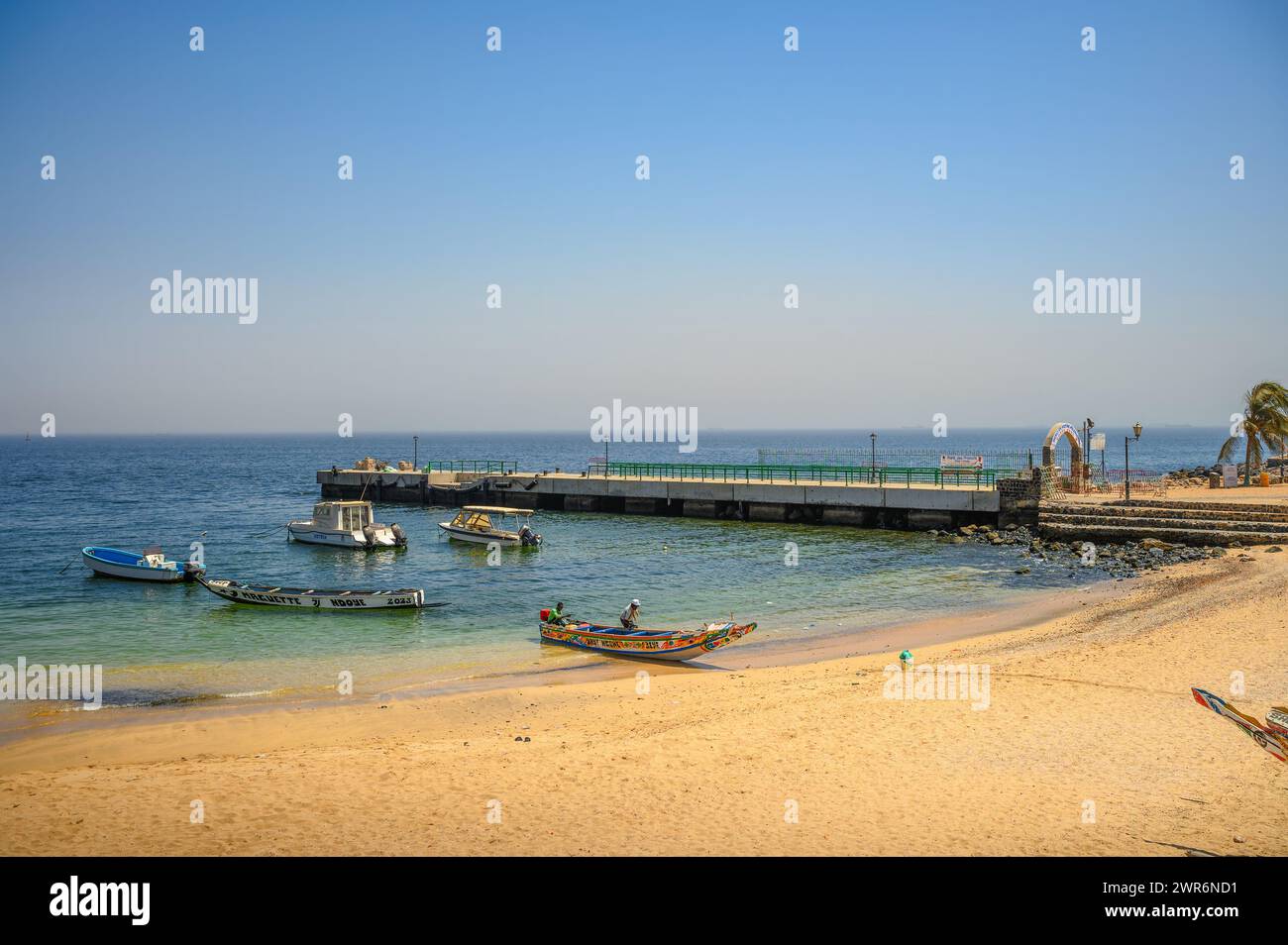 Plage calme avec des bateaux amarrés et une jetée sur l'île de Goree, Sénégal Banque D'Images