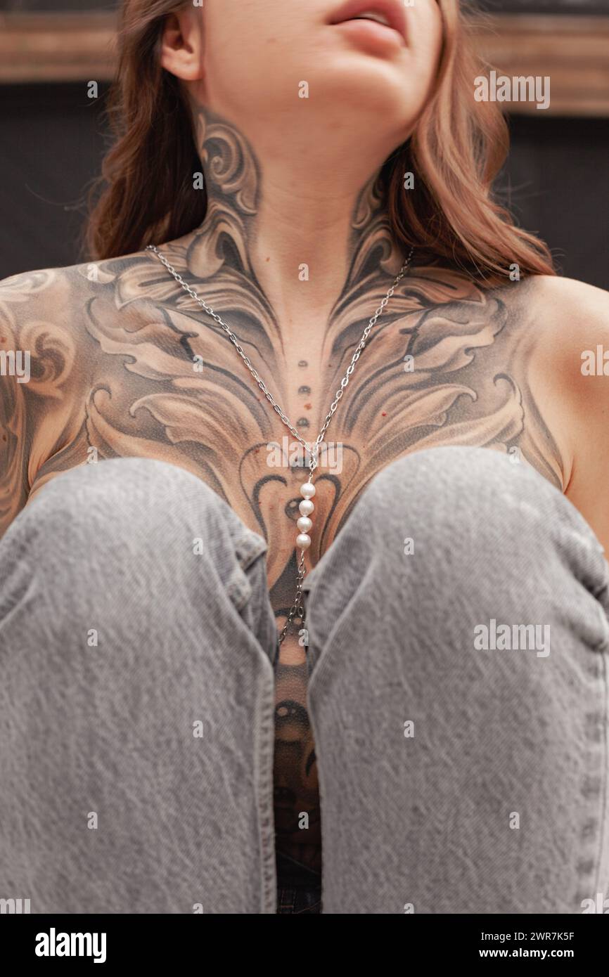 Cette image capture une vue rapprochée d'une zone de poitrine féminine avec un tatouage élaboré et artistique, mettant en évidence les détails et l'artisanat dans n Banque D'Images