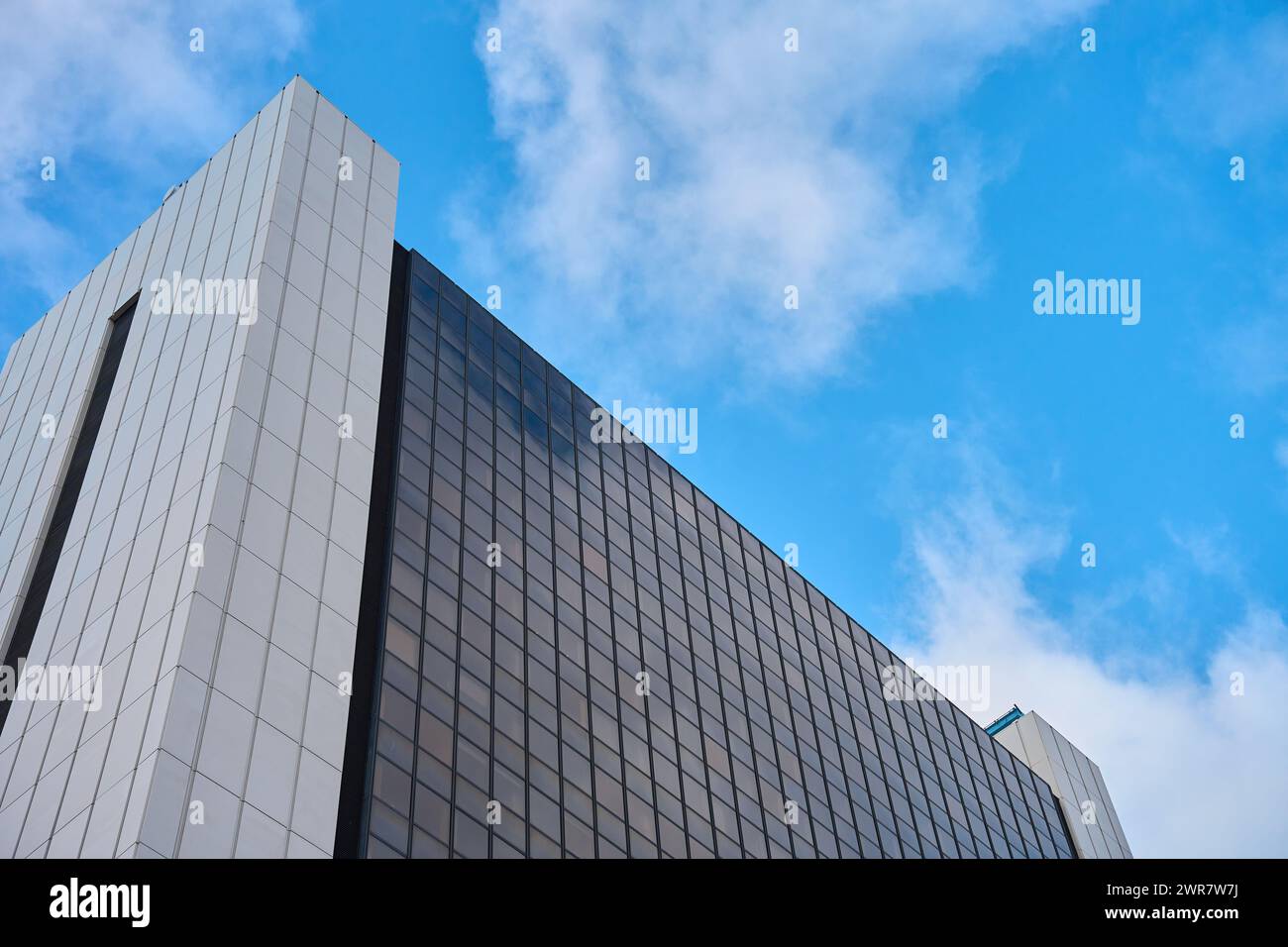 Imposant immeuble de bureaux contemporain en ville contre le ciel nuageux, extérieur d'architecture moderne avec fenêtres en verre. Banque D'Images