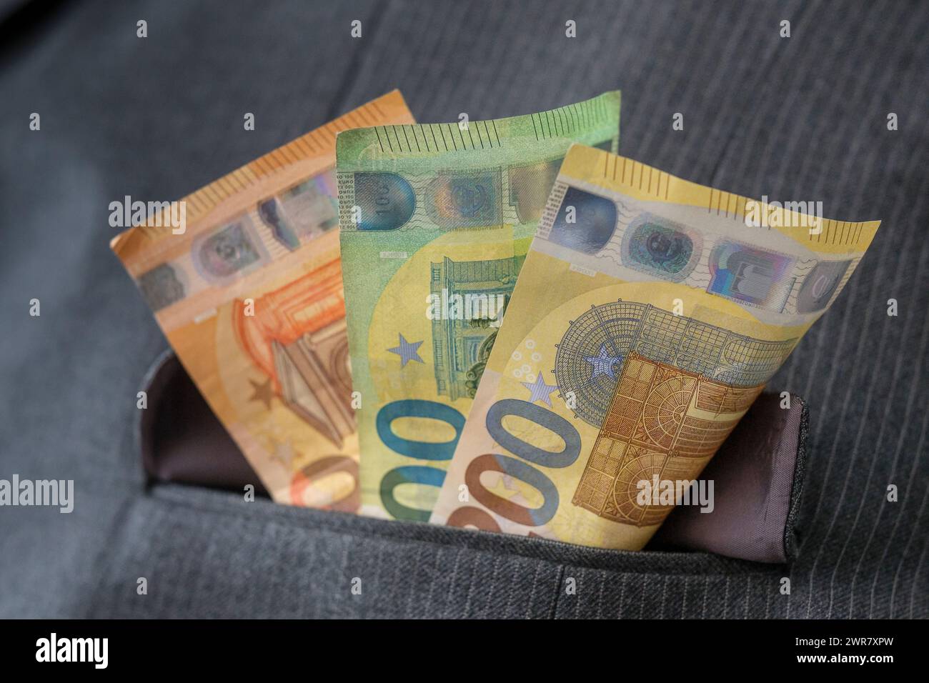 Plusieurs billets en euros dans la poche d'un costume à fines rayures Banque D'Images