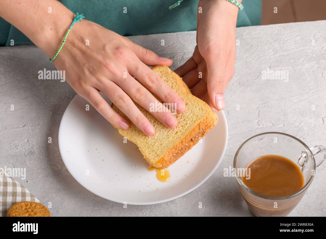 Mains féminines faisant un sandwich avec du miel et du beurre d'arachide étalant sur un morceau de pain de blé, pour prendre un petit déjeuner. Snack typique, style de vie alimentaire Banque D'Images