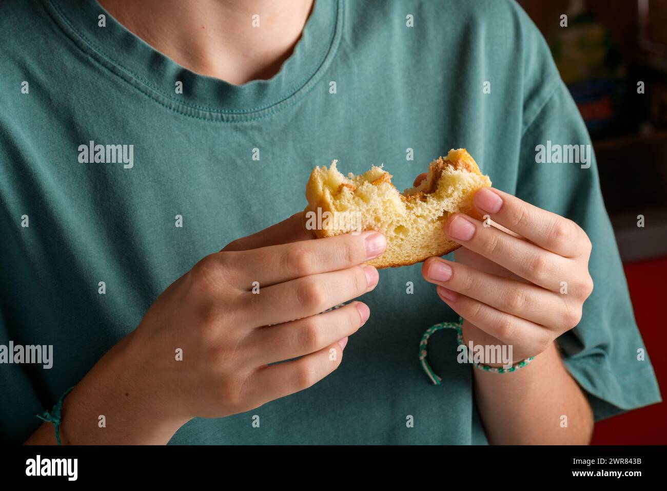 Mains féminines tenant un sandwich au beurre d'arachide mordu avec du miel de pain de blé, prendre un petit déjeuner. Femme sans visage en t-shirt de couleur vert pétrole avec Banque D'Images
