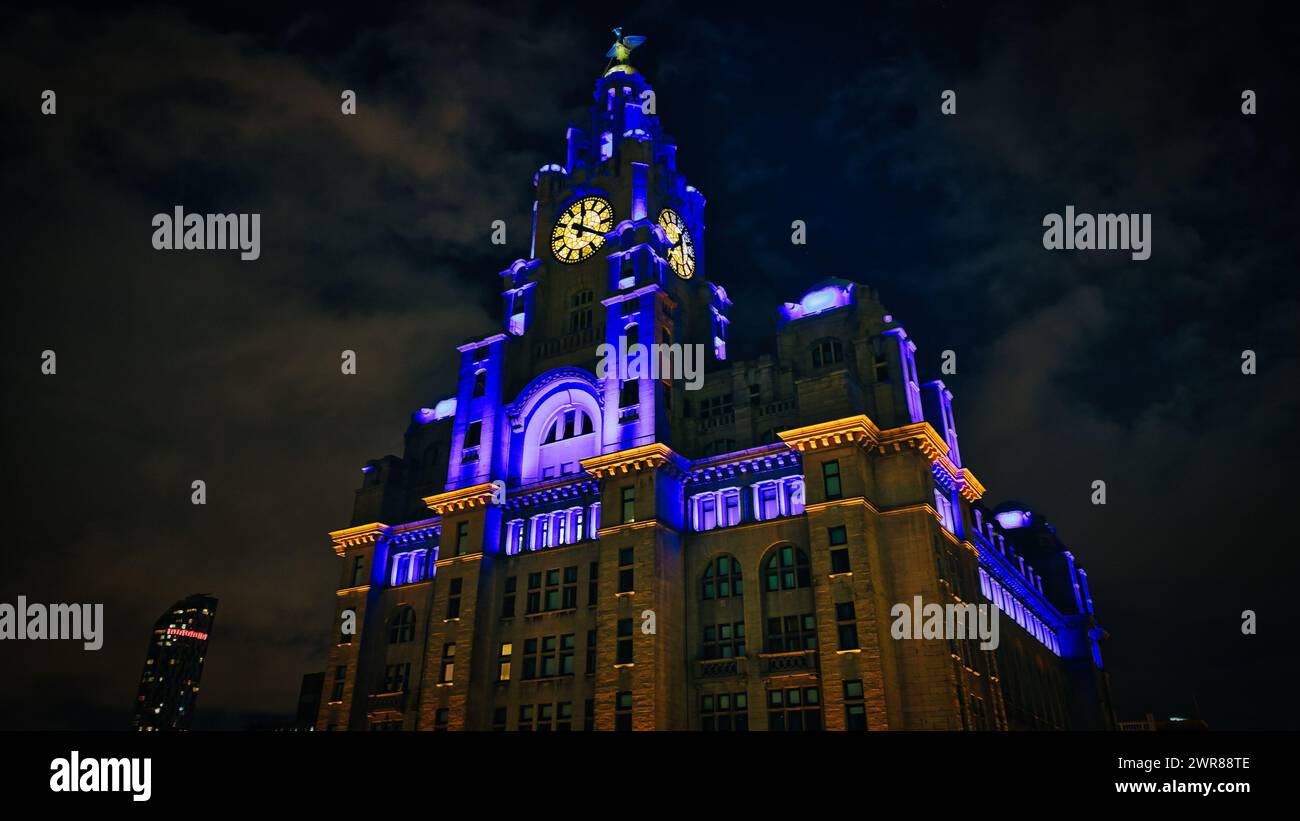 Le légendaire Royal Liver Building de Liverpool la nuit, illuminé de lumières bleues et jaunes sur un ciel sombre. Banque D'Images