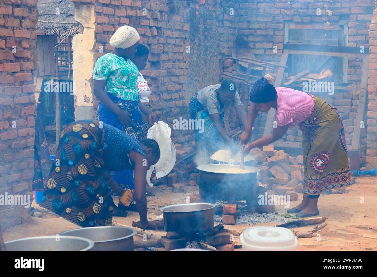 On voit des femmes en train de monter des pots sur des feux ouverts alors qu'elles préparent de la nourriture pour une fête dans le district de Mchinji. La cuisson au feu ouvert est très courante au Malawi. Banque D'Images