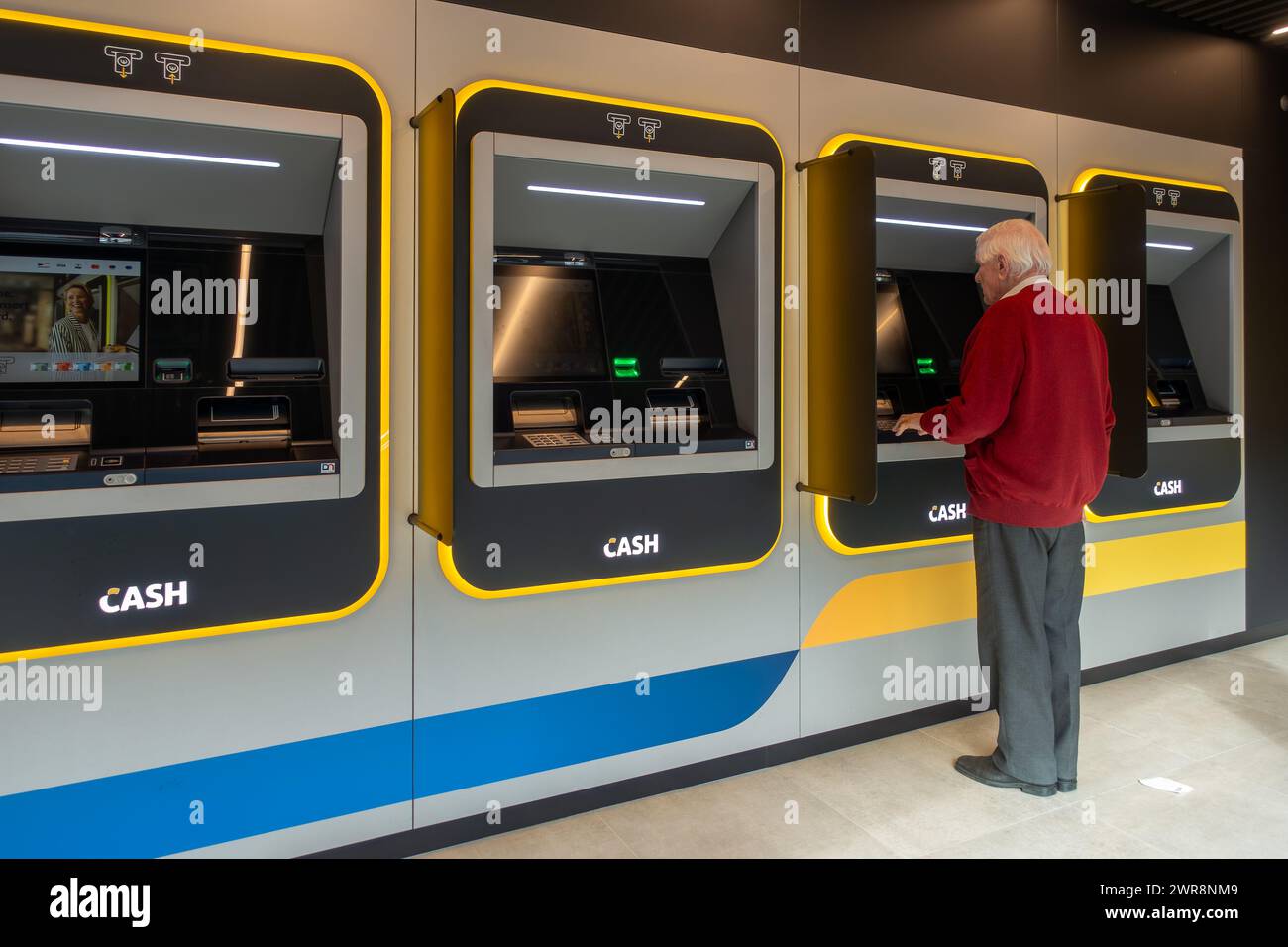 Homme âgé collectant de l'argent dans le distributeur automatique de billets intérieur du guichet Bancontact neutre bancaire en Flandre, Belgique. AUTORISATION DU MODÈLE Banque D'Images