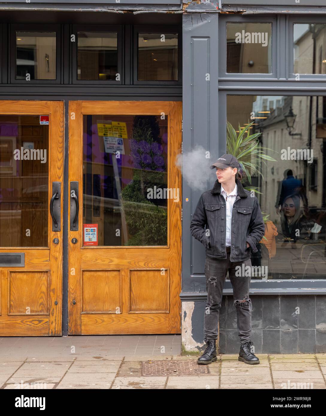 11 mars 2024. High Street, Elgin, Moray, Écosse. C'est un jeune homme qui souffle de la fumée devant un café-bar sur High Street dans le centre-ville. Banque D'Images