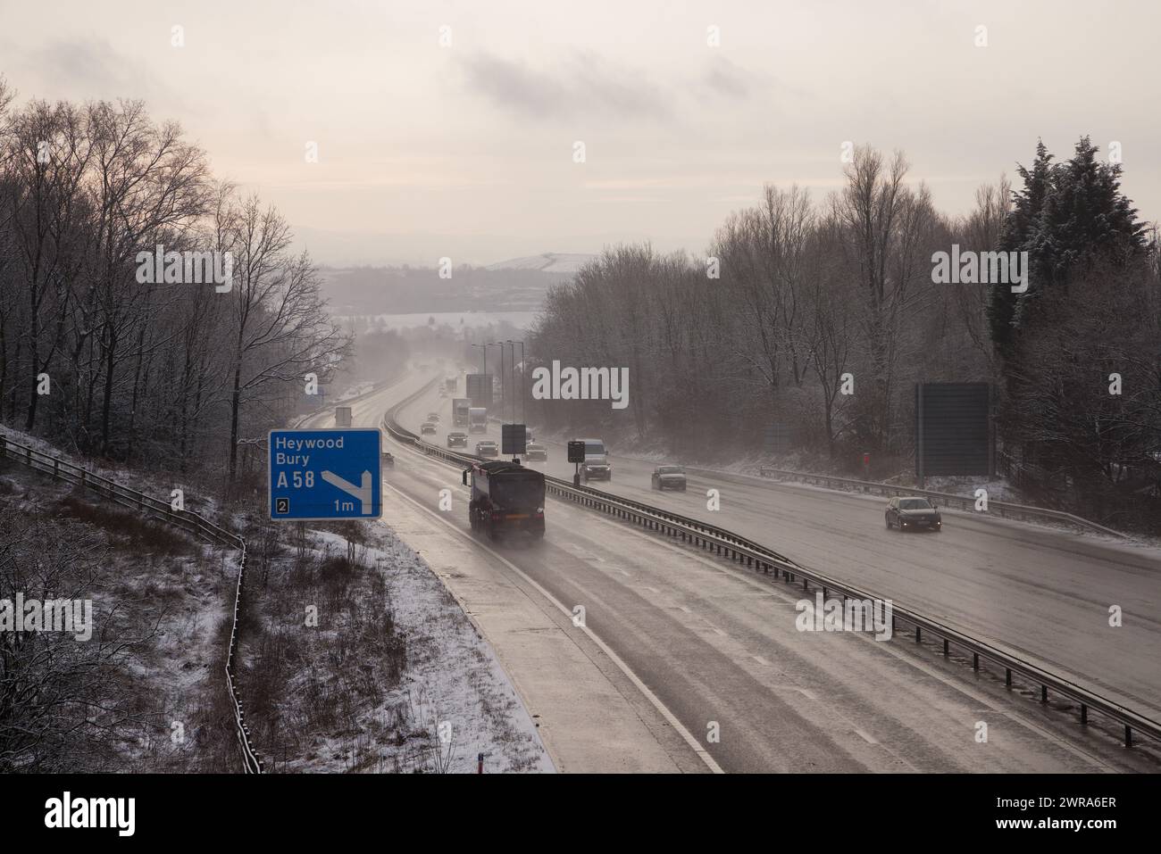 Un camion et des voitures sur une route humide hivernale sur la M56 avec bois, Bury, Greater Manchester. Banque D'Images