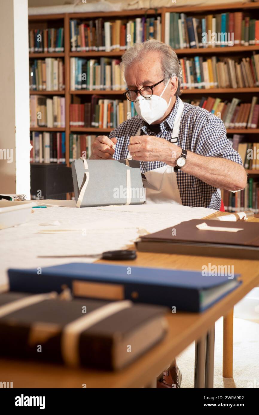 21/05/21 conservateur et ancien ébéniste, Mike Browne (75) répare un livre de la collection libraryÕs. Les restaurateurs de livres retournent au PAI Banque D'Images