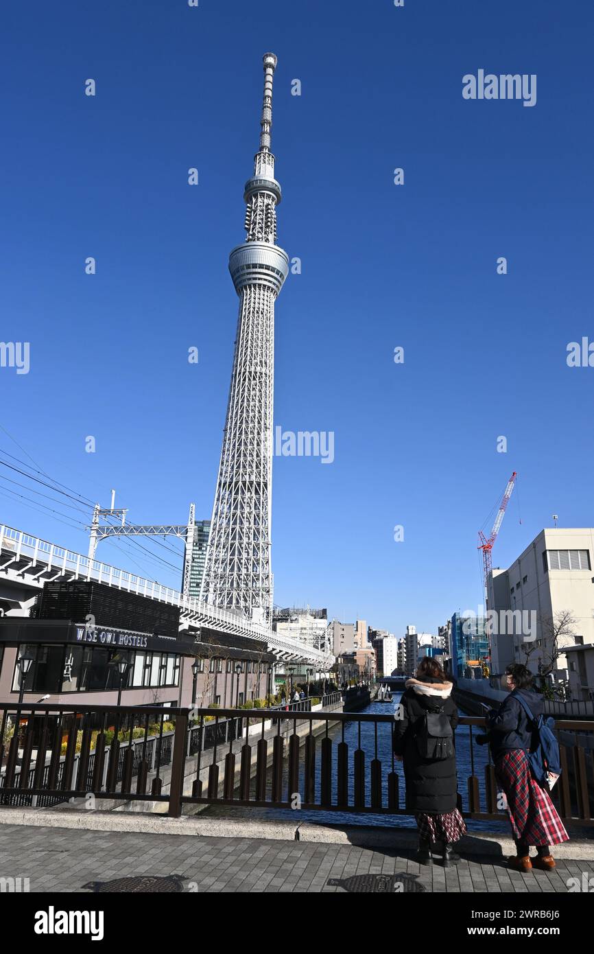 Deux personnes regardent le Tokyo Skytree depuis un pont par une journée ensoleillée – Sumida City, Tokyo, Japon – 27 février 2024 Banque D'Images