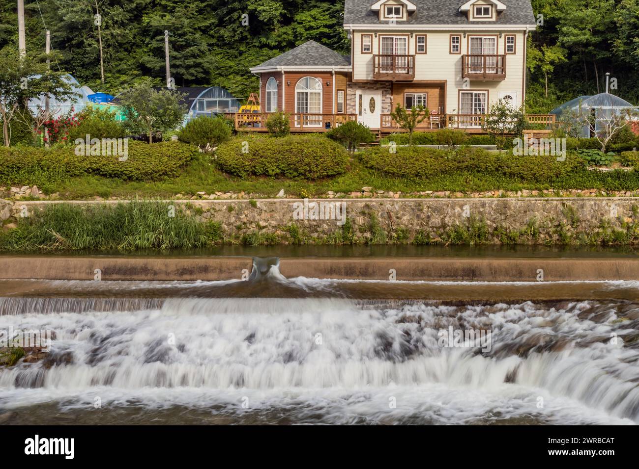 Les maisons élégantes donnent sur une petite cascade en cascade sur la rive de la rivière, en Corée du Sud Banque D'Images