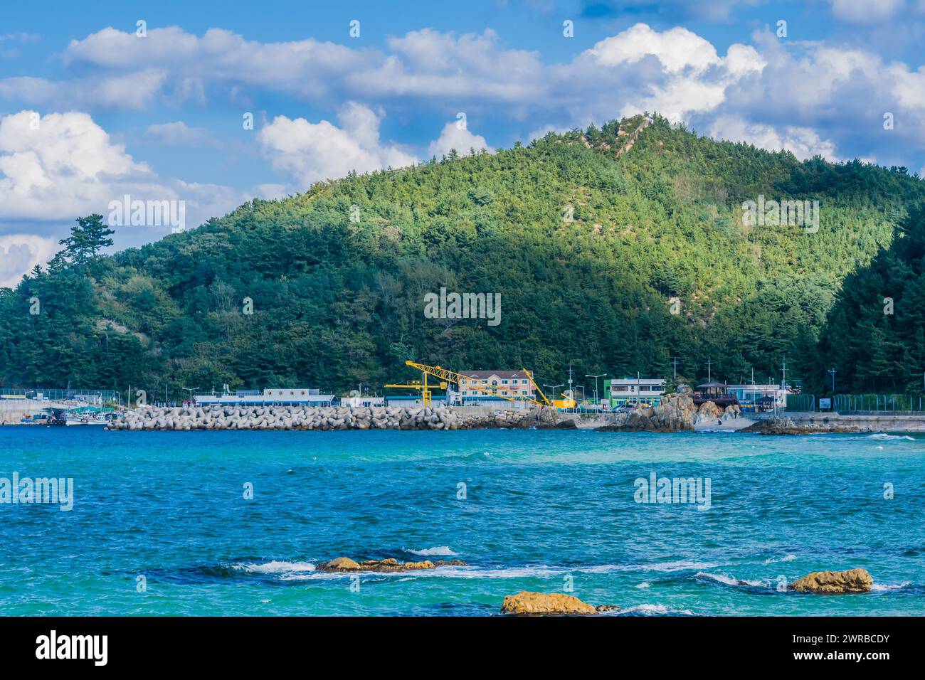 Vue panoramique d'un village côtier par la mer avec des montagnes et un ciel bleu, en Corée du Sud Banque D'Images