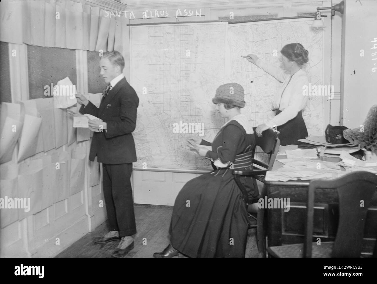 Santa Claus Ass'n, photographie montre un homme et deux femmes regardant des lettres envoyées à l'Association du Père Noël à New York City., entre CA. 1915 et env. 1920, négatifs en verre, 1 négatif : verre Banque D'Images