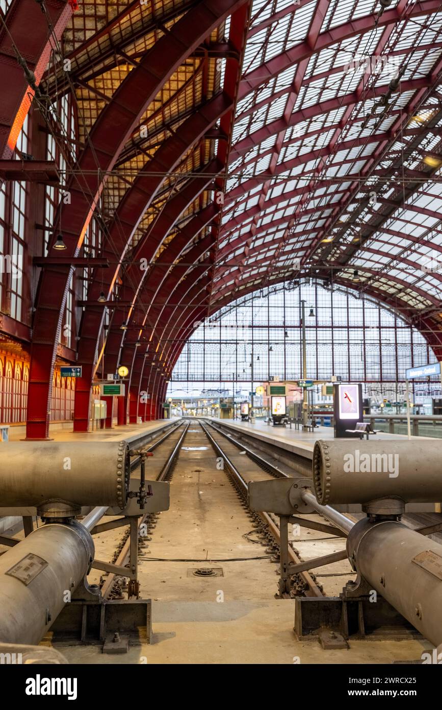 Anvers, Belgique, le 25 janvier 2024, la symétrie architecturale de l'intérieur de la gare centrale d'Anvers est capturée du point de vue des voies, menant le regard vers la façade vitrée lointaine. La métallurgie des arcs de toit au-dessus de la tête, un témoignage des prouesses de conception de l'ère industrielle. Le vide des pistes offre un moment de calme en contraste avec l'agitation habituelle de la station. Symétrie structurelle à l'intérieur de la gare centrale d'Anvers. Photo de haute qualité Banque D'Images