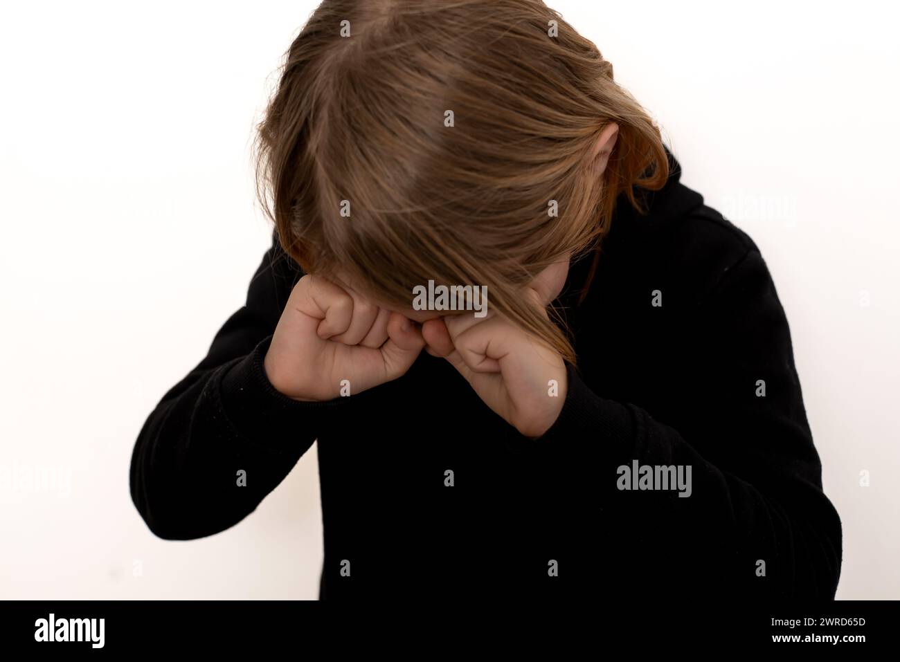 Un jeune garçon, privé de sommeil et aux cheveux longs, révèle un troisième œil fatigué, placé sur un fond de blanc pur Banque D'Images