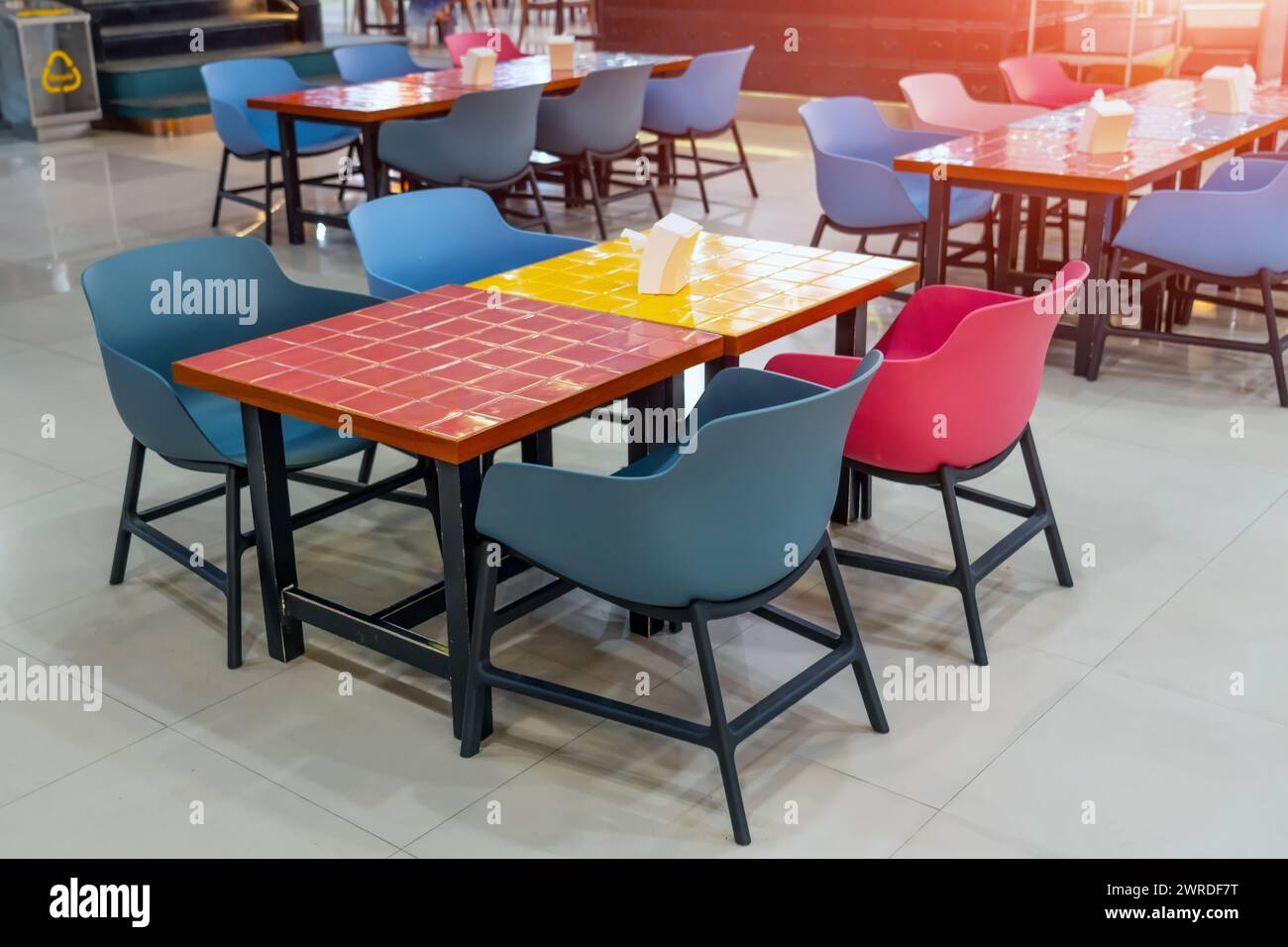Chaises en plastique et tables en bois avec des carreaux de céramique colorés brillants dans des carrés Banque D'Images
