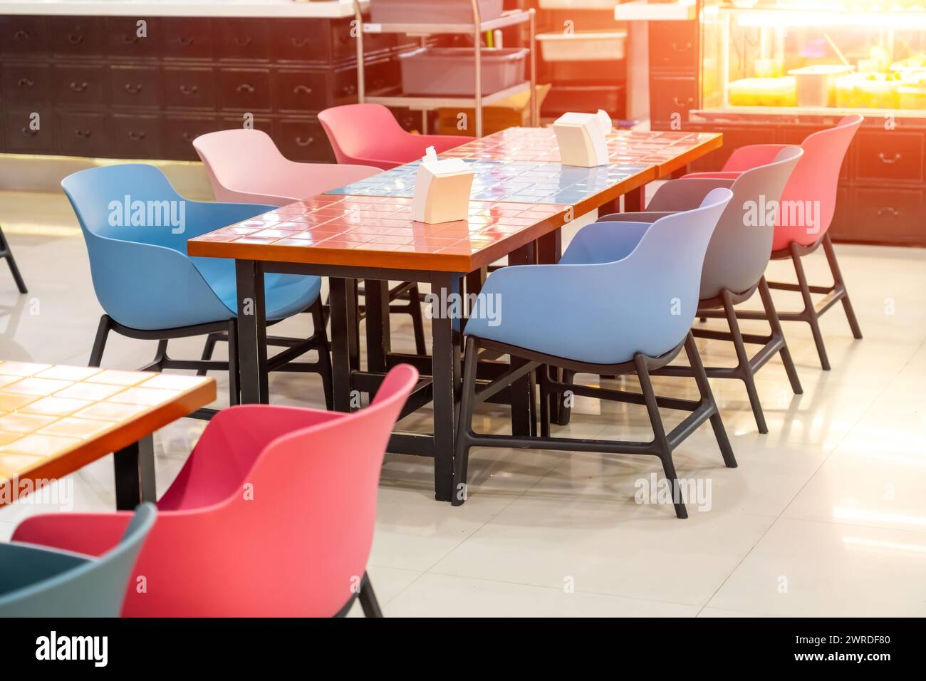 Chaises en plastique et tables en bois avec des carreaux de céramique colorés brillants dans des carrés Banque D'Images