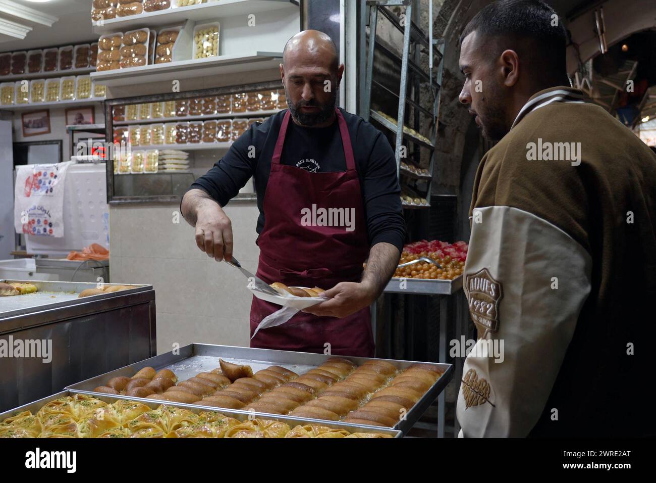Les Palestiniens achètent des pâtisseries sucrées après la pause de leur jeûne pendant le premier jour du Ramadan le 11 mars 2024 à Jérusalem. Israël Banque D'Images
