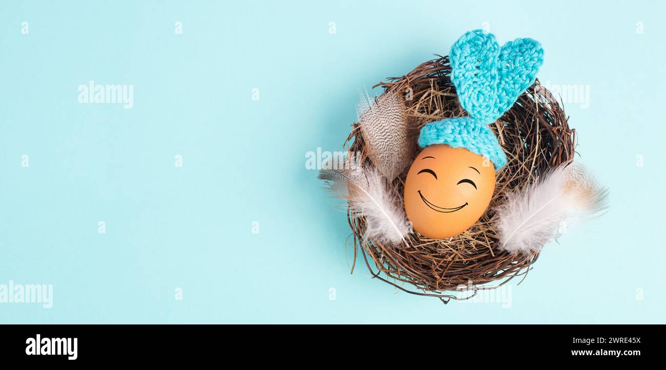 Lapin de Pâques ou oeuf de lapin dans un nid d'oiseau, oreilles et plumes crochetées, vacances de printemps, couleur bleue Banque D'Images