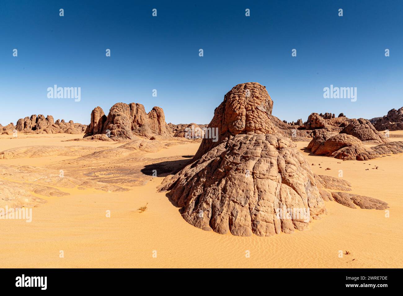 Paysage Tadrart dans le désert du Sahara, Algérie. Formations rocheuses de grès jetant un coup d'œil sur le sable jaune Banque D'Images