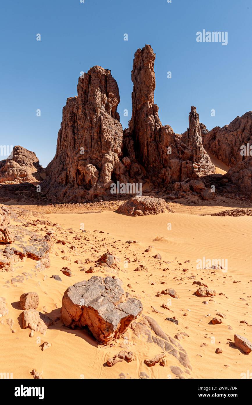 Paysage Tadrart dans le désert du Sahara, Algérie. Une pierre couchée sur le sable devant une formation rocheuse abrupte Banque D'Images