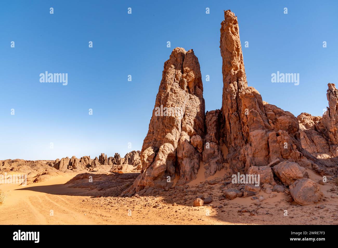 Paysage Tadrart dans le désert du Sahara, Algérie. Des sommets rocheux de grès rouge émergent du sable jaune. Banque D'Images