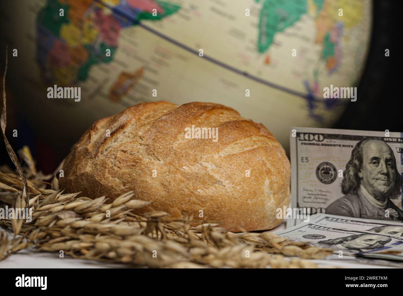 Crise alimentaire mondiale du blé, représentée par un globe, épis de blé et d'argent, dollars, isolés sur fond noir. Banque D'Images