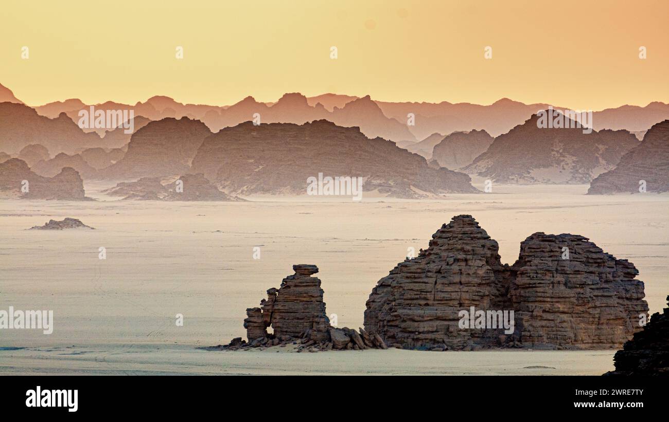 Paysage Tadrart dans le désert du Sahara, Algérie. Au lever du soleil, les formations rocheuses qui émergent du sable forment des ombres chinoises. Banque D'Images