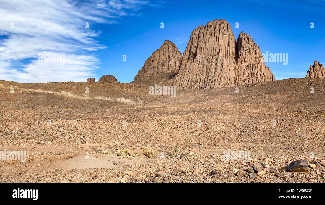 Paysage de Hoggar dans le désert du Sahara, Algérie. Une vue sur les montagnes et les organes de basalte qui se dressent autour du chemin de terre qui mène à Assekrem. Banque D'Images