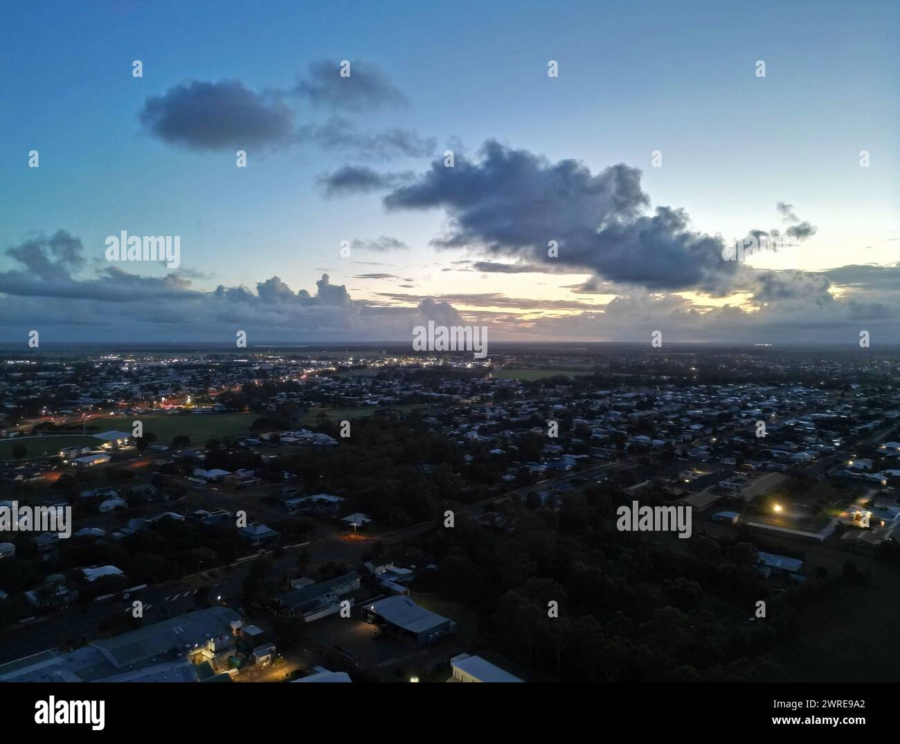 Vue panoramique en soirée de la ville avec des lumières incandescentes sous des nuages sombres Banque D'Images