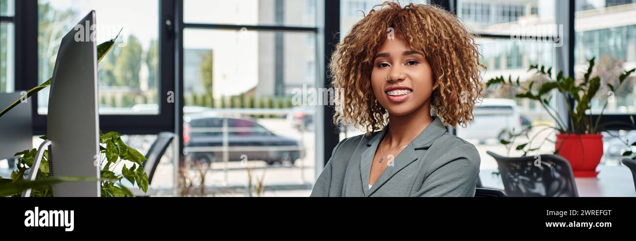heureuse femme d'affaires afro-américaine assise au bureau devant l'écran d'ordinateur dans le bureau, bannière Banque D'Images