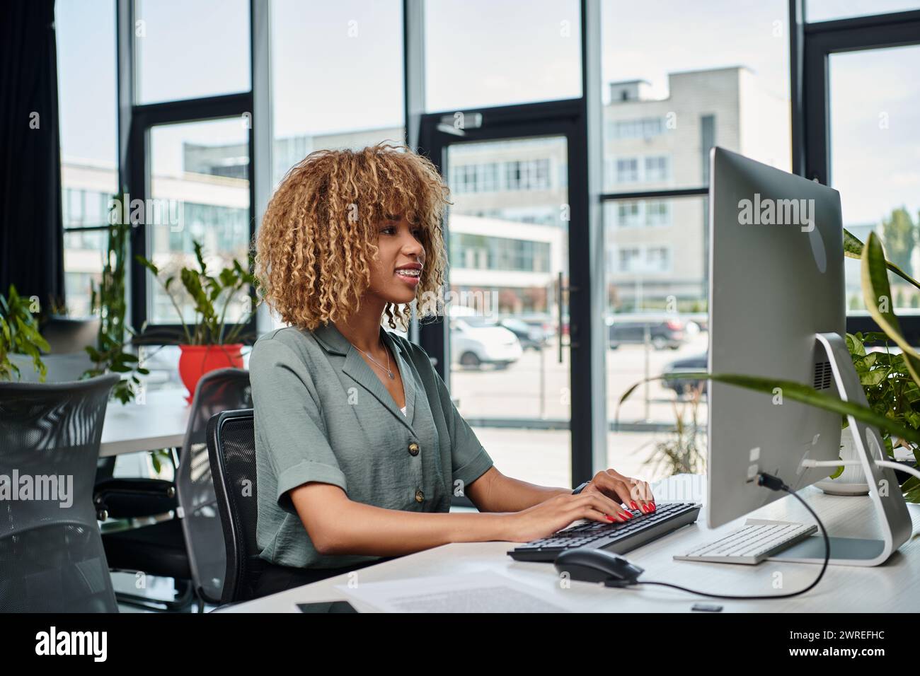 positif jeune responsable afro-américain travaillant au bureau devant l'écran d'ordinateur dans le bureau Banque D'Images